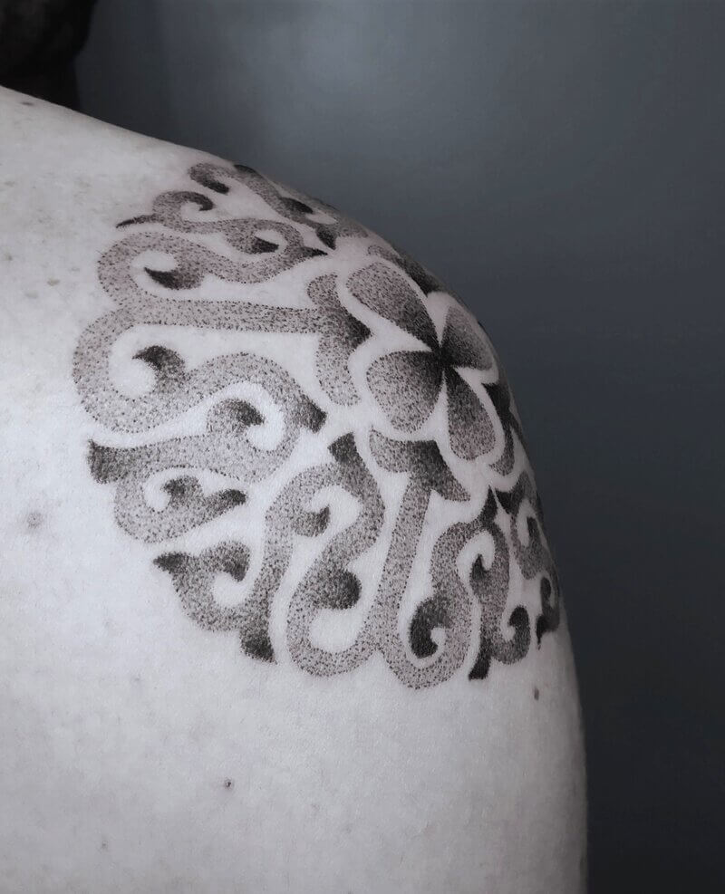 Un tatouage handpoke d'un motif Kazakhstan sur l'épaule
